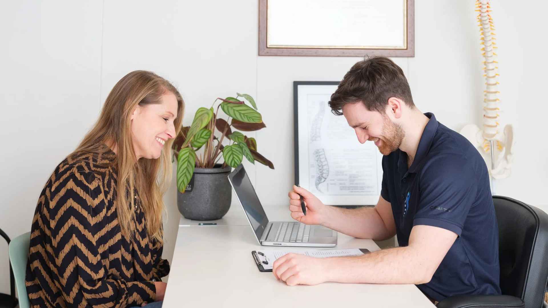 Chiropractor discussing treatment plan with patient at desk during consultation at Waterland Chiropractie Culemborg