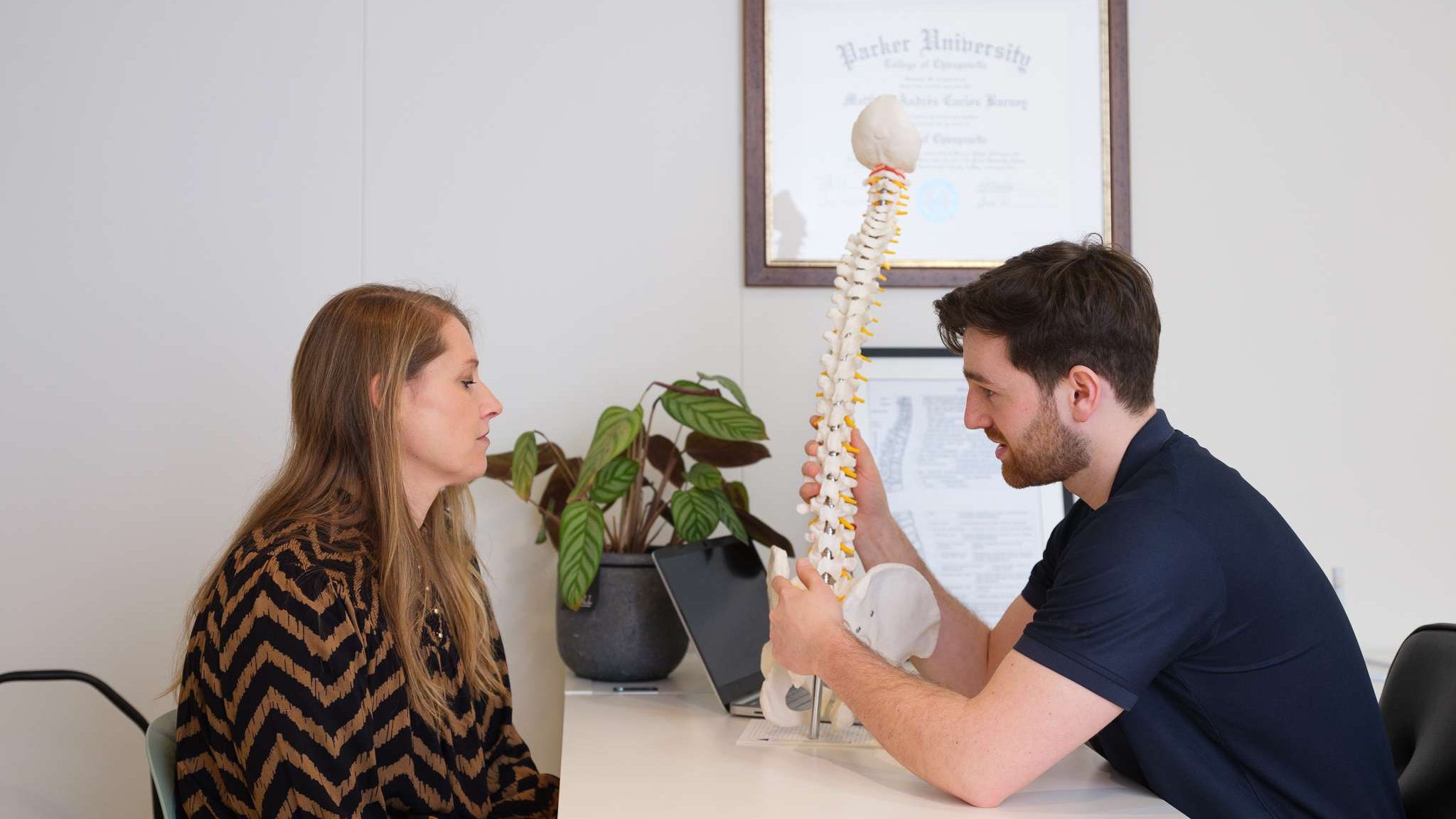 Chiropractor Ben Arctander legt de wervelkolom uit aan een patient in Tiel